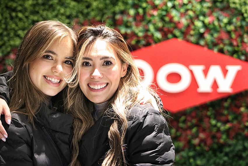 Two women smiling in front of a Dow sign